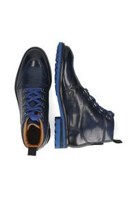 Un par de botas de cuero azul marino con cordones y suelas azules, ojales de metal y interior acolchado en color marrón, mostradas desde vistas superior y lateral.