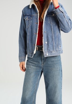 Ruututakki, jossa on villa-kauluksen, vaaleansininen väri, etutaskut, nappikiinnitys, yhdistettynä punaiseen neuleeseen ja leveisiin farkkuihin.