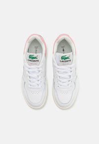 Baskets en cuir blanc avec un accent de talon rose, arborant un logo de crocodile vert, bout rond et un design à lacets.