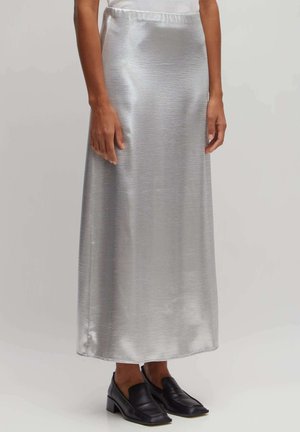 Silberne Satin-Maxi-Rock mit glatter Textur, ausgestattet mit einem Taillenbund und kombiniert mit schwarzen Leder-Loafers.