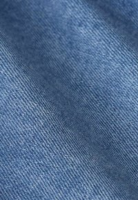 Gros plan sur la texture du tissu en denim bleu montrant un motif de tissage diagonal.