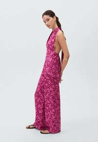 Jumpsuit rosa brillante con motivo a foglie, pantaloni larghi e scollatura profonda. Tessuto leggero con una texture liscia.
