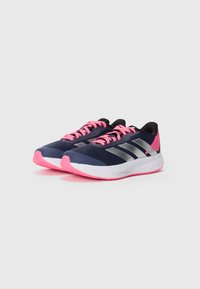 Baskets de sport navy avec des accents argentés, des lacets roses et une tige en mesh texturé. Semelle intermédiaire blanche et semelle extérieure rose pour l'adhérence.