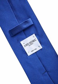 Blå slips med diagonala ränder i texturerad tyg, med en vit etikett med svart text som säger "JOHN HENRIC SWEDEN Made in Italy."