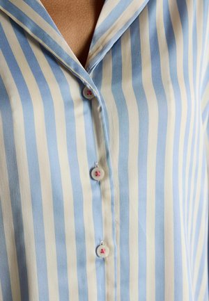 Světle modrá košile s bílými pruhy a límečkem. Obsahuje ozdobné knoflíky s růžovými akcenty podél předního zapínání. Hladký povrch.