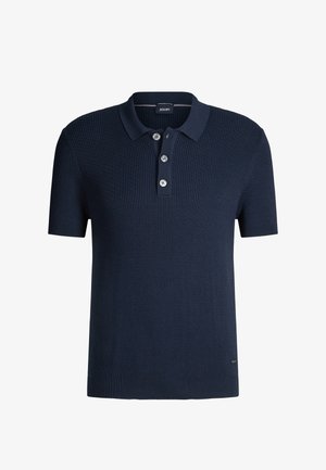 Granatowy dzianinowy t-shirt polo o teksturowanym prążkowanym wzorze, z trzema guzikami na listwie i subtelnym logo w pobliżu krawędzi. Krótkie rękawy.