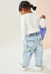 Jeans din denim bleu deschis cu imprimeuri florale în acuarelă, talie elastică și două buzunare pe spate. Asortați cu un top alb cu mâneci lungi și adidași albi.