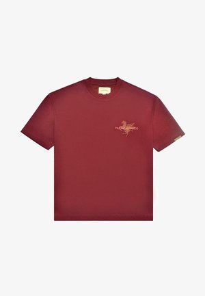 T-shirt court à manches courtes maroon avec col rond et petit graphique orange avec le texte "PAS DE MONACO" sur la poitrine gauche.