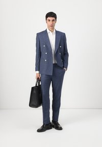 Blå teksturert dobbeltradet dress med sølvknapper, hvit skjorte og svart lærveske. Slim-fit bukser og svarte pensko er inkludert.