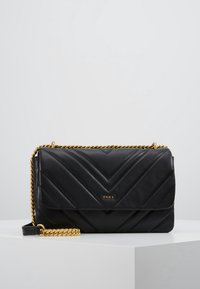 Musta tikattu nahkakäsilaukku, jossa on kultaketju. Siinä on chevron-kuvio ja pieni DKNY-logo kullassa edessä.