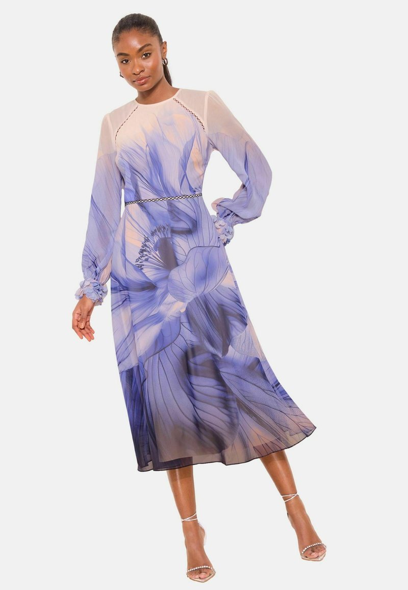 Langærmet kjole i gennemsigtigt stof med et blomstret mønster i blå og lavendel. Kjolen har en figursyet overdel og en flydende A-formet silhuet.
