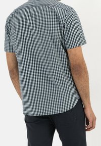 Camicia a maniche corte con motivo a quadri vichy bianco e nero, orlo curvo e vestibilità rilassata. Realizzata in un tessuto traspirante.