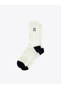 Calcetines blancos con textura de canalé, con detalles en azul marino en la punta y el talón. Presentan un número "II" bordado en el costado, hechos de una tela suave y flexible.