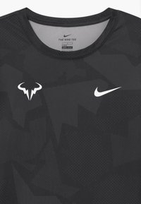 Sort atletisk T-shirt med DRI-FIT teknologi, med et geometrisk mønster, rund halsudskæring og hvide Nike- og kvæg-logoer på forsiden.