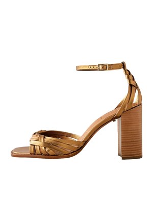 Goldene Riemchensandale mit Knöchelriemen und Blockabsatz, mit geflochtenen Riemen über dem Zeh und einem holzstrukturierten Absatz.