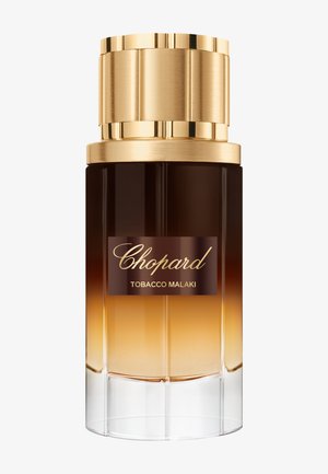 Flakon perfum Chopard Tobacco Malaki z gradientowym brązowo-bursztynowym szkłem i dużą, teksturowaną złotą nakrętką.