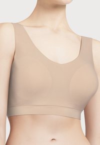 Beige sømløs bh med brede stropper, lav V-hals og en jevn, elastisk tekstur. Har subtil formgivning for komfort og støtte.