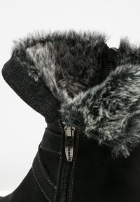 Černé semišové boty s umělou kožešinou na manžetě, boční zip a kontrastní švy. Měkká textura a teplý design.