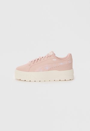 Baskets synthétiques roses avec une surface texturée, arborant un logo blanc, une semelle épaisse couleur crème et de subtils accents irisés sur le côté.