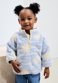 Fleece pullover in light blue and cream, featuring a zip front and abstract patterns. Soft texture with bold design elements.