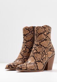 Brown faux snakeskin ankle boots, with a pointed toe and block heel. Features a side zipper and textured pattern for visual interest.