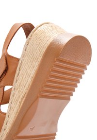 Sandal in pelle marrone con tacco a zeppa, dotata di una base testurizzata, un'area della punta liscia e una suola in tan rigata per una migliore aderenza.