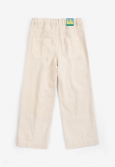 Pantalon beige pour tout-petit avec ceinture élastique, deux poches arrière et un petit patch logo coloré en haut au centre.