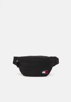 Sac banane noir en nylon avec un compartiment zippé, arborant un patch logo à l'avant en rouge, blanc et bleu. Design compact avec une sangle ajustable.