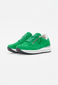 Roheline sametiga sneakers, millel on tekstuuriga viimistlus, valge kontsa aktsent ja külgipaigaldus. Must kummist tallaga ja triibuline vaheõhk.