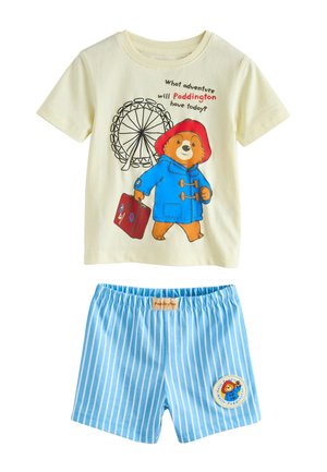 Children's outfit with cream t-shirt featuring Paddington Bear in blue coat and red hat, and blue and white striped shorts with Paddington patch.
