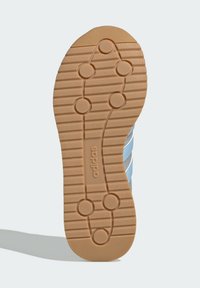 Světle modrá sportovní obuv se strukturovanou gumovou podrážkou, která má vlnitý vzor, kruhové trakční body a logo "adidas" na mezipodešvi.