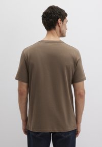 Braunes kurzärmliges T-Shirt mit klassischem Rundhalsausschnitt und einem glatten, leicht strukturierten Stoff. Die Passform ist locker, mit einem schlichten Design.