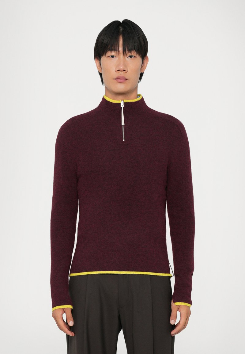 Bordeaux kleurige sweater met rits en gele afwerking aan de kraag en onderkant. Zachte textuur, lange mouwen en een aansluitend ontwerp voor een moderne silhout.