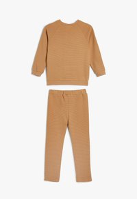 Beige tvådelat set i bomull med en ribbad långärmad sweatshirt med rund halsringning och matchande åtsittande byxor med elastisk midja.