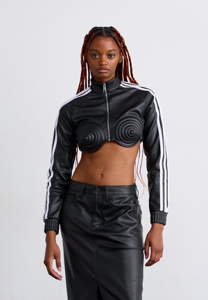Veste cropped en faux cuir noir avec des détails en relief en spirale, fermeture éclair à l'avant et rayures blanches sur les côtés ; associée à une jupe en cuir noire taille haute.