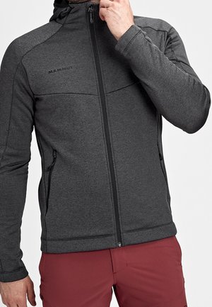 Szara bluza polarowa z wysokim kołnierzem, zamkiem błyskawicznym na całej długości oraz kieszeniami zapinanymi na zamek. Posiada płaskie szwy i fakturowany materiał. Logo z lewej górnej strony.
