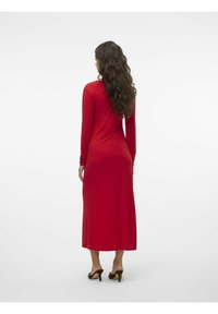 Abito lungo rosso a maniche lunghe con una silhouette aderente, realizzato in tessuto morbido, che arriva a metà polpaccio, con scollatura rotonda e una leggera drappeggiatura.