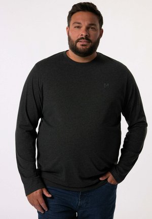 Dunkelgraues Langarmshirt aus weichem Stoff mit Rundhalsausschnitt und dezentem Logo-Detail auf der Brust, kombiniert mit blauen Jeans.