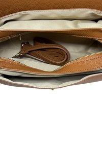 Brązowa skórzana torebka o fakturowanej powierzchni, wyposażona w wiele przegródek i długi odpinany pasek. Wnętrze wyłożone jasną tkaniną.