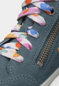 Kék velúr tornacipő színes pöttyös cipőfűzőkkel és ezüst cipzárral az oldalon.