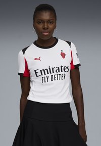 Hvid kortærmet trøje med røde og sorte detaljer. Har teksten og logoet "Emirates Fly Better". Letvægts og åndbart stof.