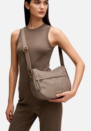 Donna con outfit marrone senza maniche tiene una borsa a tracolla taupe con texture, cerniera dorata e logo "Laura Biagiotti".