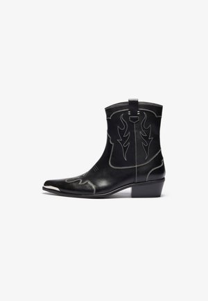 Black leather cowboy boots with pointed toe, prominent flame stitching, silver accents, pull tab, and a low stacked heel.