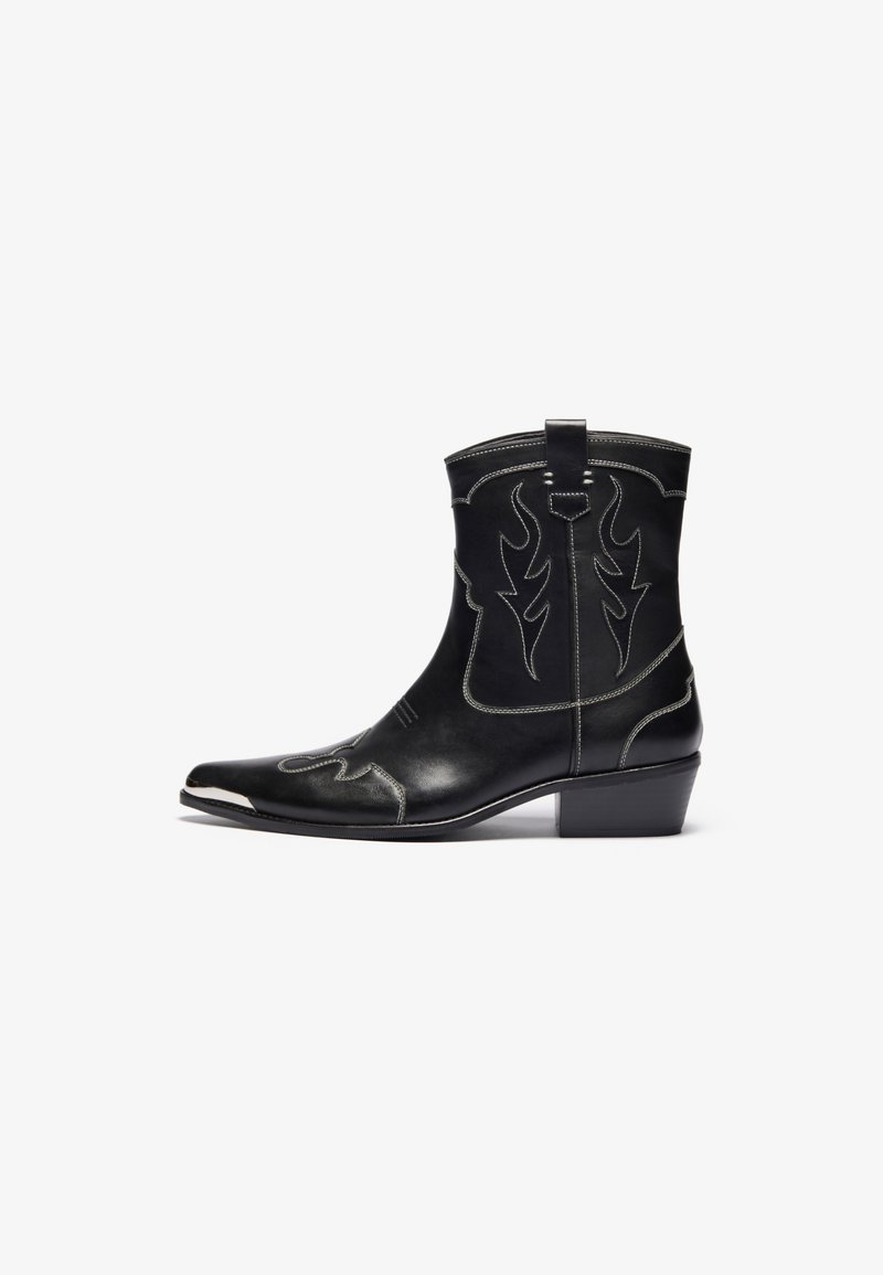 Bottes de cowboy en cuir noir avec un bout pointu, des coutures enflammées proéminentes, des accents argentés, une boucle de tirage et un talon bas empilé.