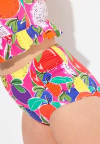 Färggäng set för badkläder med en volang topp och högmidjade botten, tillverkad av ett mjukt, elastiskt tyg med fruktryck i livliga färger.