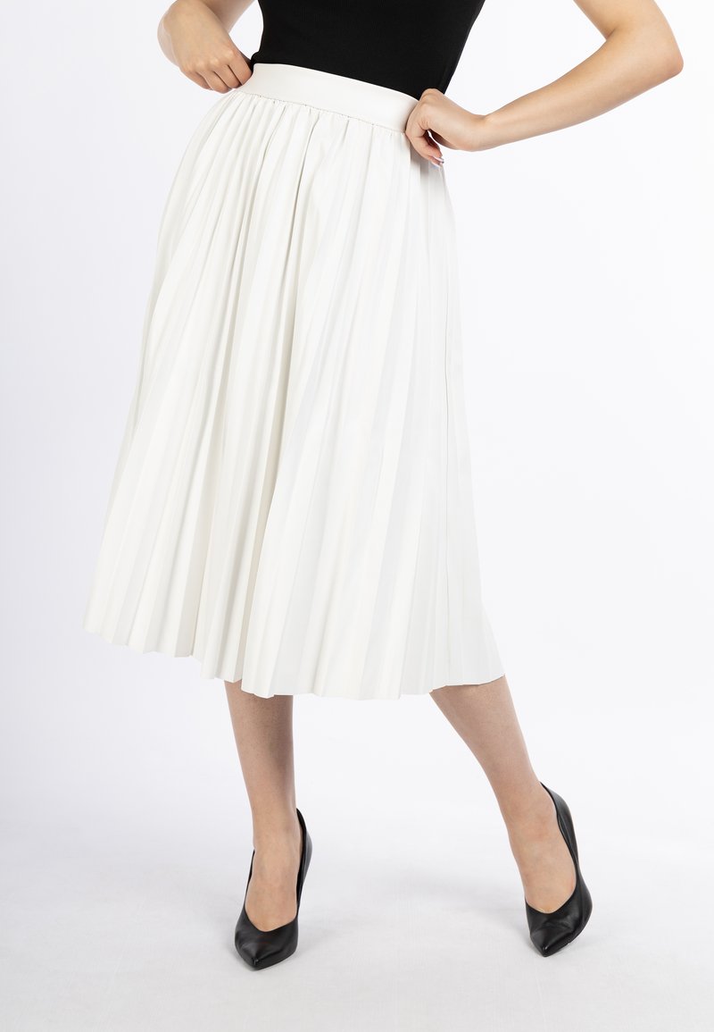 Witte plissé midi-rok met een gladde tailleband, vloeiende stof en zachte textuur, gecombineerd met zwarte puntige pumps.