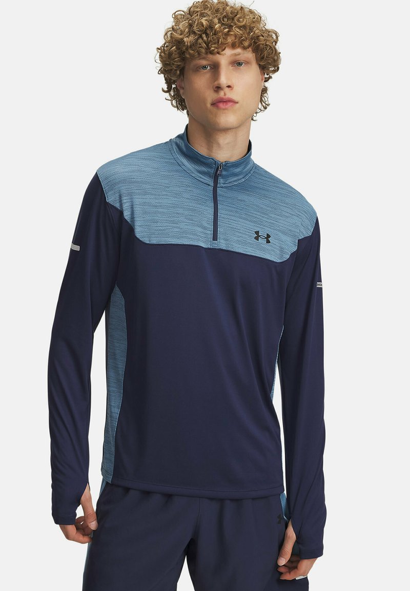 Tumesinine pikakä sleeves, sportlik top, millel on helesinine tekstuuriga paneel ja lukuga krae. Omab peegeldavaid elemente varrukatel ja rinna logo.