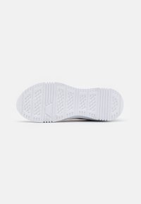 Sula av en sneaker, främst vit med strukturerade greppmönster, med ribbor och utskärningar för dragkraft och flexibilitet.