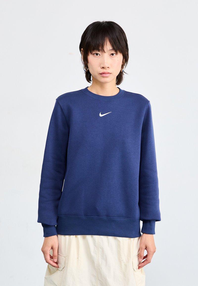 Μπλε ναυτικού φούτερ από μαλακό ύφασμα, με στρογγυλή λαιμόκοψη, μακριά μανίκια και μικρό λευκό λογότυπο Nike στο στήθος.
