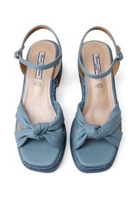 Sandali in pelle blu con dettaglio a nodo sulla punta, forma quadrata della punta, cinturino alla caviglia e accenti in modo intrecciato sul tacco. L'interno presenta una fodera imbottita.